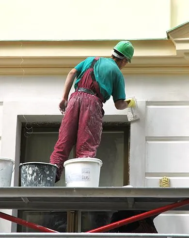 Professional painter on scaffolding completing a commercial building exterior painting project